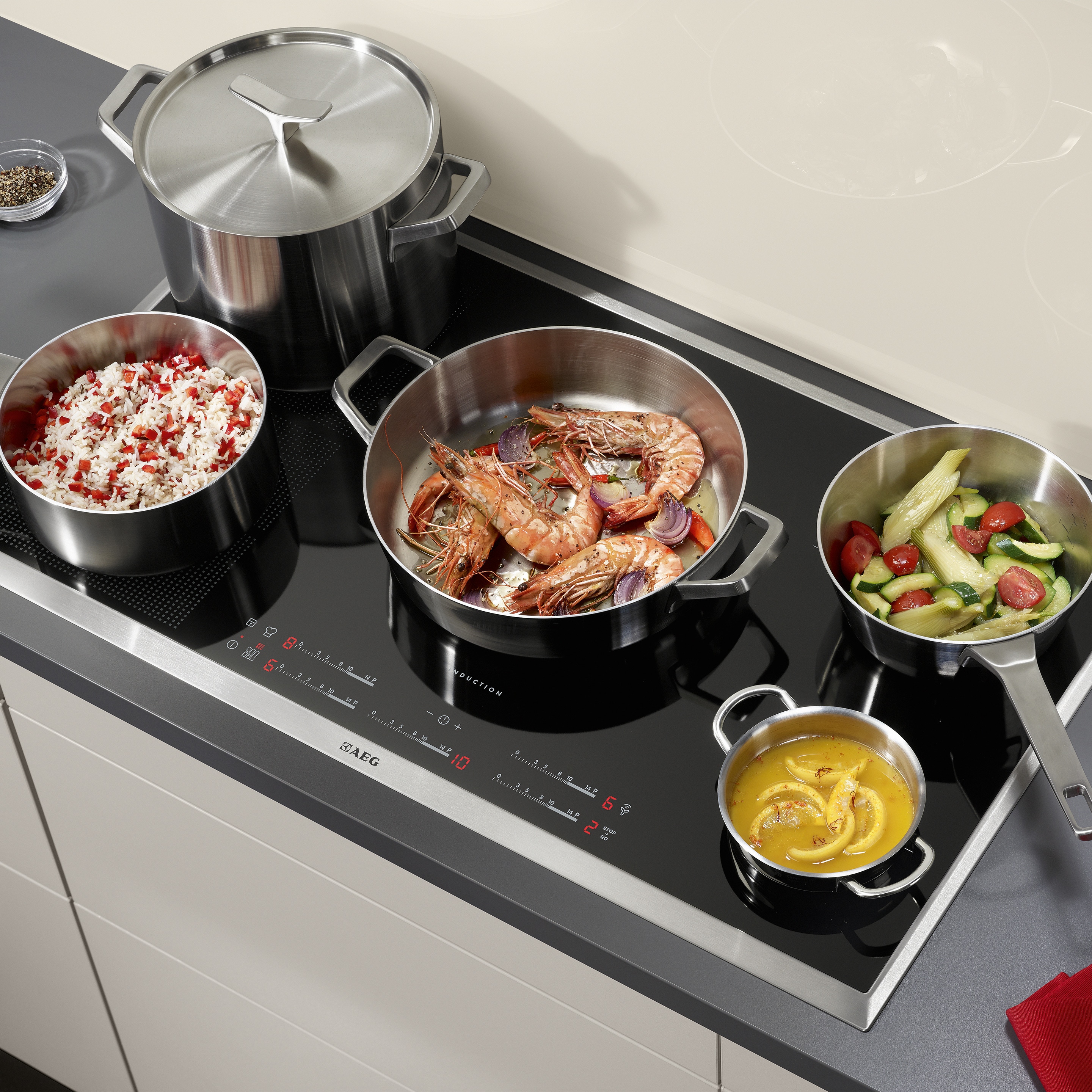 Indukční varná deska Electrolux, na které se v pánvích připravují různé pokrmy